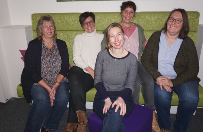5 Frauen sitzend auf grünem Sofa, in die Kamera lächelnd