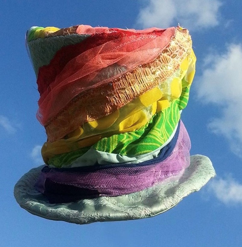 Zylinderförmiger Hut mit verschiedenen und farbigen Stoffbahnen besetzt vor blauem Himmel